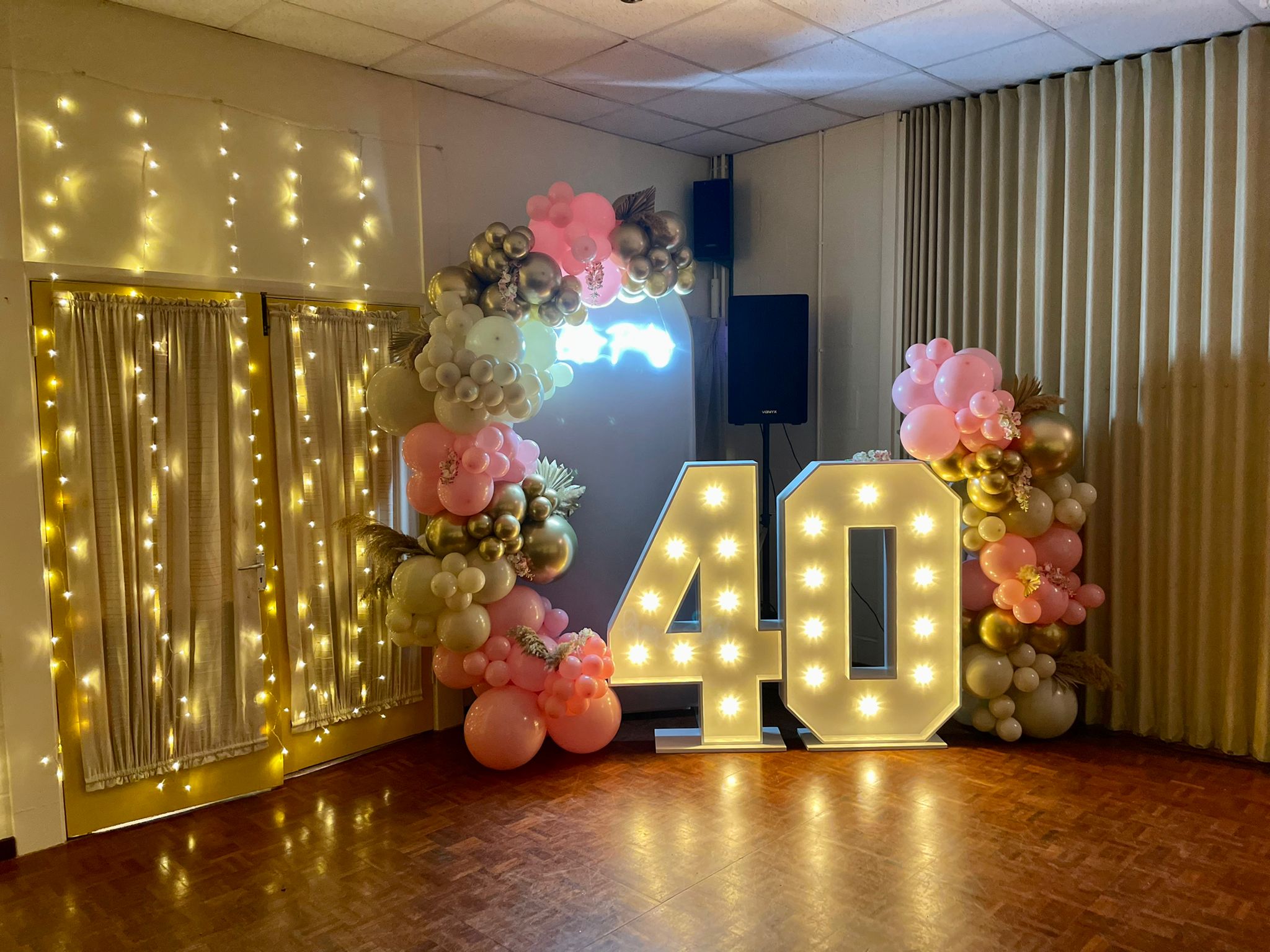 party decoration with a large light bulb lit 40 and balloon arch